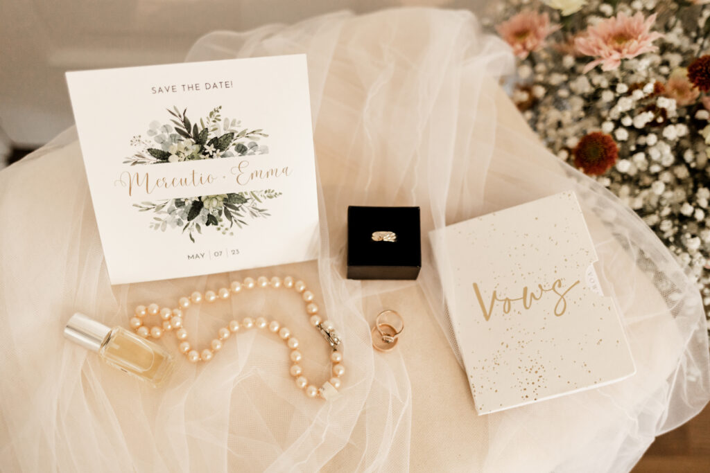 Details, including perfume, a pearl necklace, vow book, rings, and an invitation, at this Estate 248 wedding in Langley, British Columbia