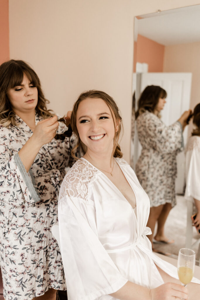 The bride smiling while getting her hair done at an Estate 248 wedding in Langley, British Columbia