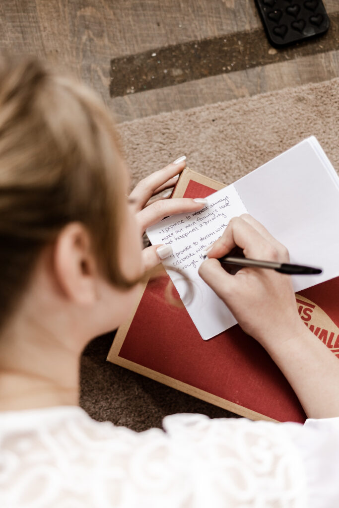 An over the should view of the bride writing out her vows in the vow book at an Estate 248 wedding in Langley, British Columbia