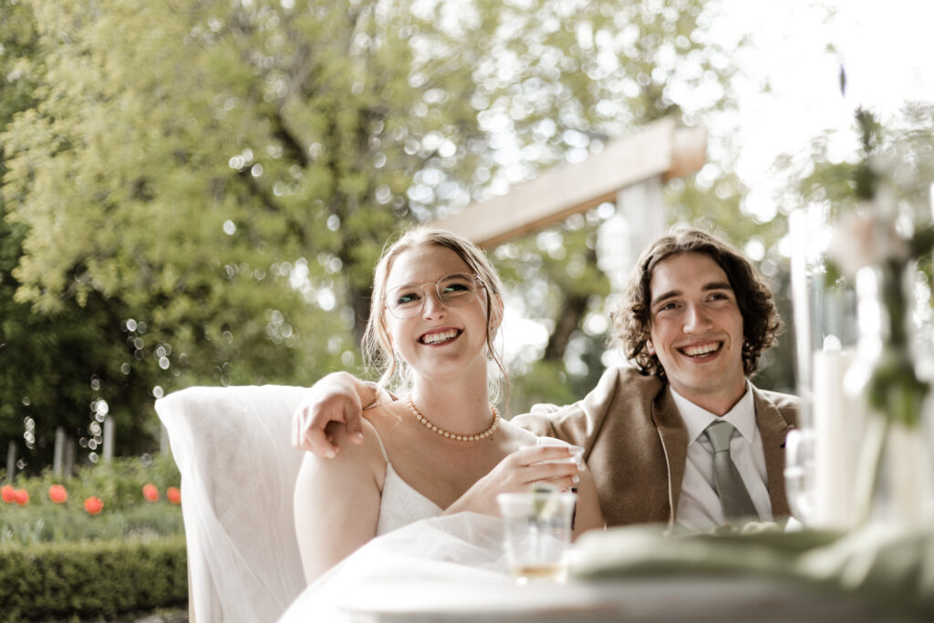 The bride and groom smile as they listen to speeches at their Estate 248 wedding in Langley, British Columbia