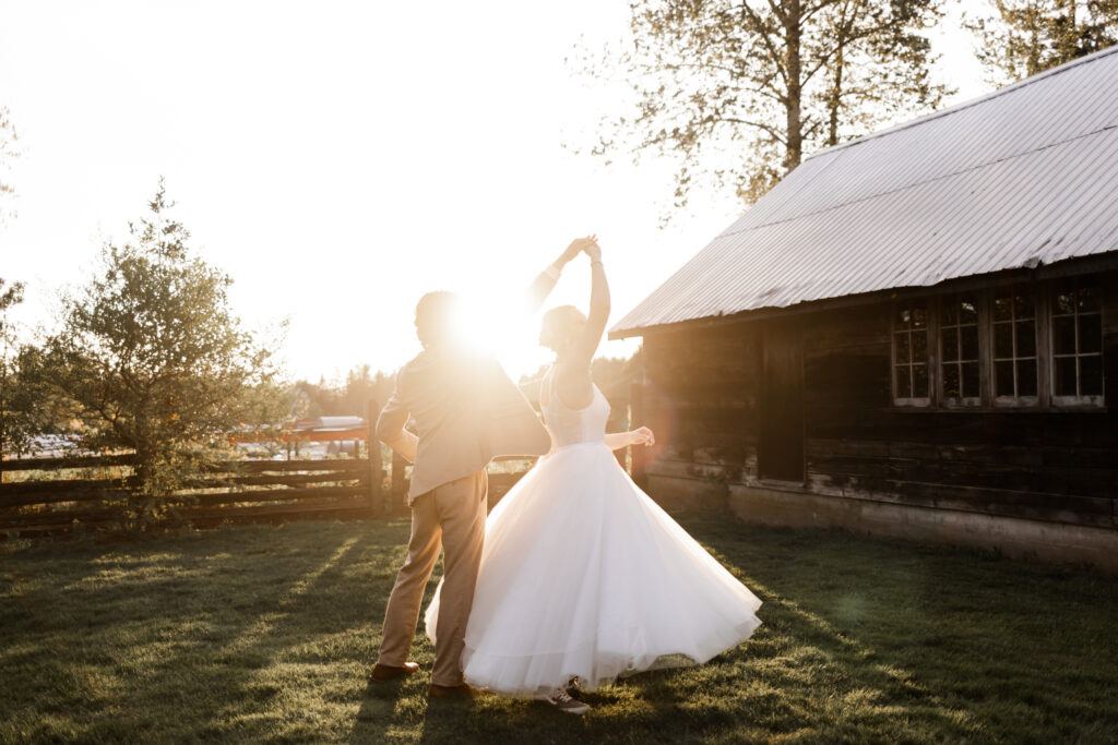 the groom twirls the bride as the golden suns shines in from behind at this Estate 248 wedding in Langley, British Columbia