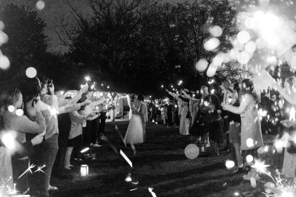 the bride and groom share a kiss as the run down a makeshift aisle of guests holding sparklers at their Estate 248 wedding in Langley, British Columbia