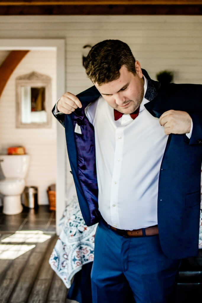 Groom puts on suit jacket at this Bird's Eye Cove wedding