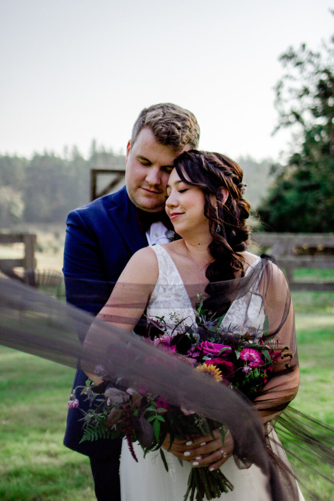 Groom hugs bride from behind at this Bird's Eye Cove wedding