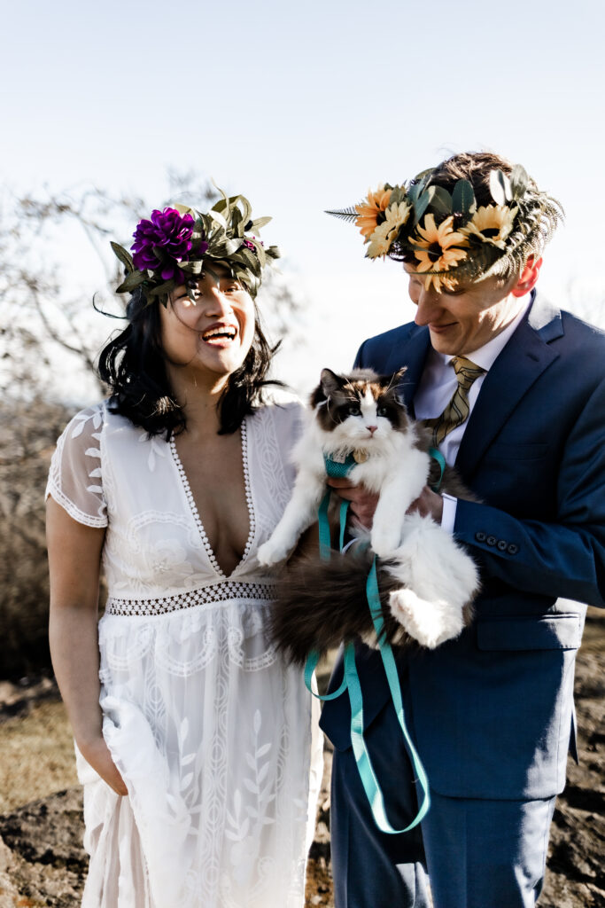 A couple laugh while holding their cat at a Mount Douglas elopement.