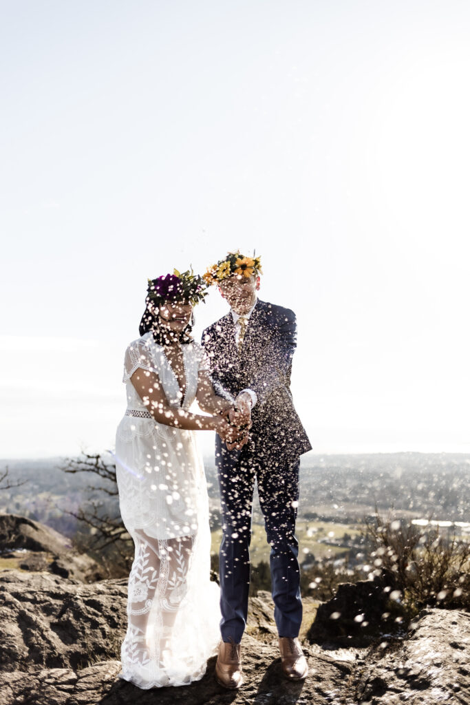 A bride and groom spray a bottle of champagne in celebration at their Mount Douglas elopement.