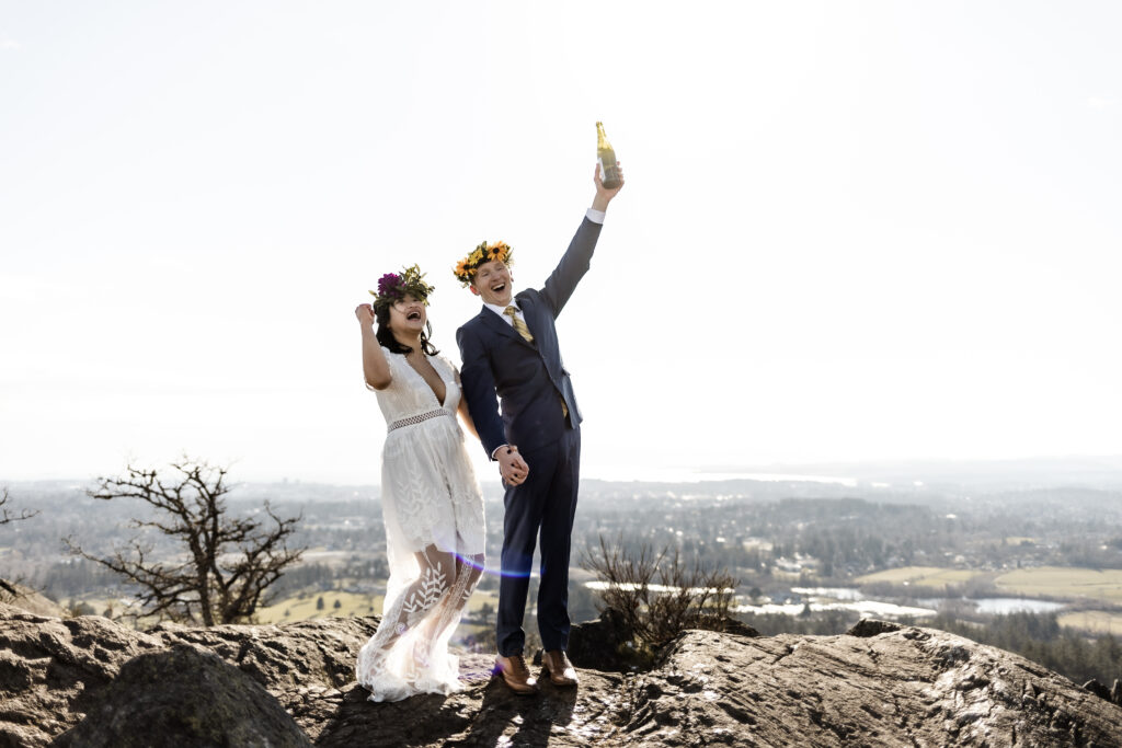 The bride and groom cheer, holding up the champagne bottle, at their Mount Douglas elopement