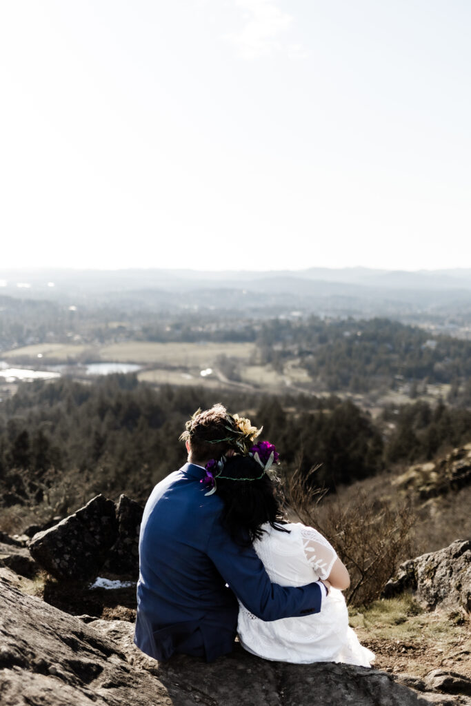 The bride and groom cuddle as they admire the view of the city at the Mount douglas elopement