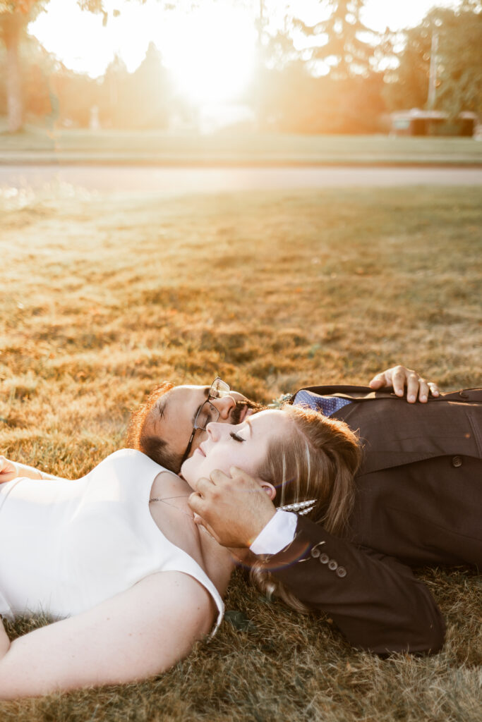 bride and groom lay on the grass together at golden hour at this Victoria wedding