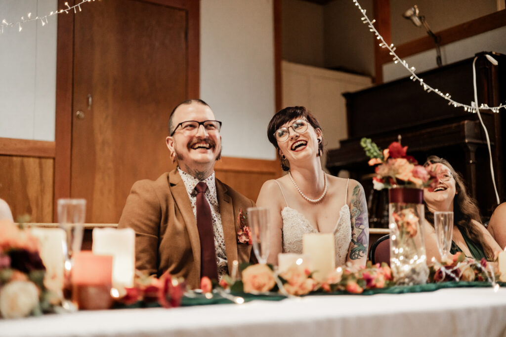 bride and groom laugh during speeches at this punk wedding in Victoria, BC