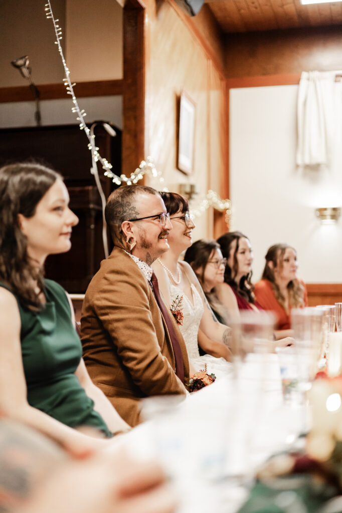 bride and groom smile during speeches at this punk wedding in Victoria, BC