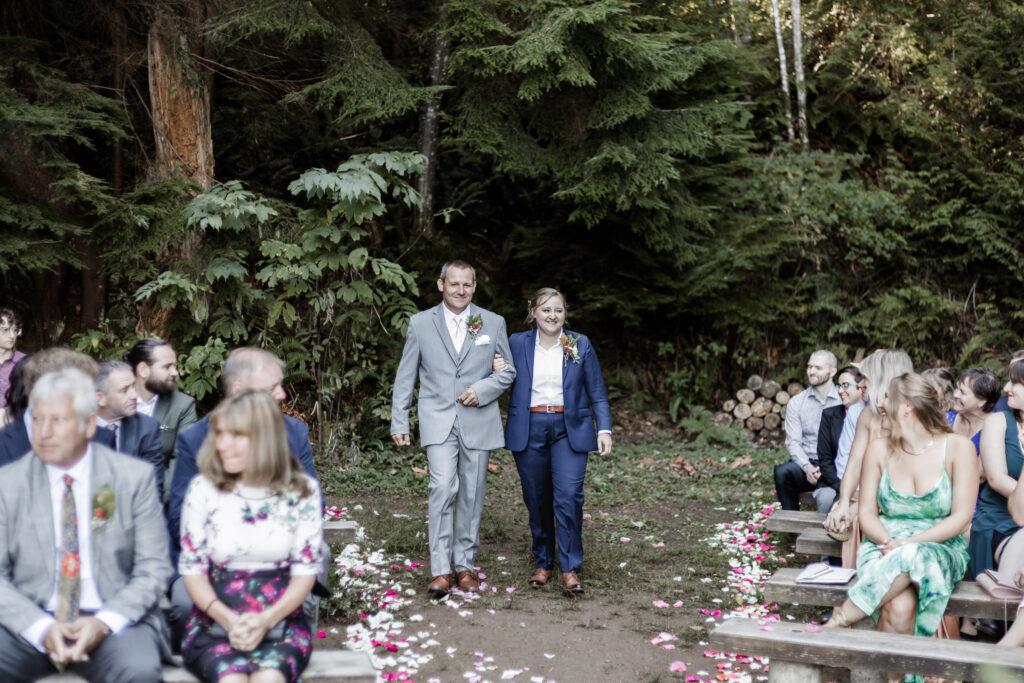 Kirsten walks down the aisle with her father at her Camp Elphinstone wedding.