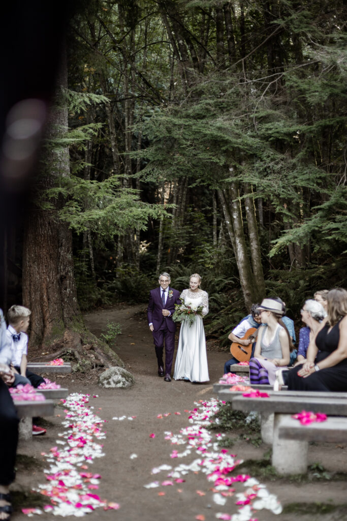 Morgan walks down the aisle in her wedding dress at this Camp Elphinstone wedding.