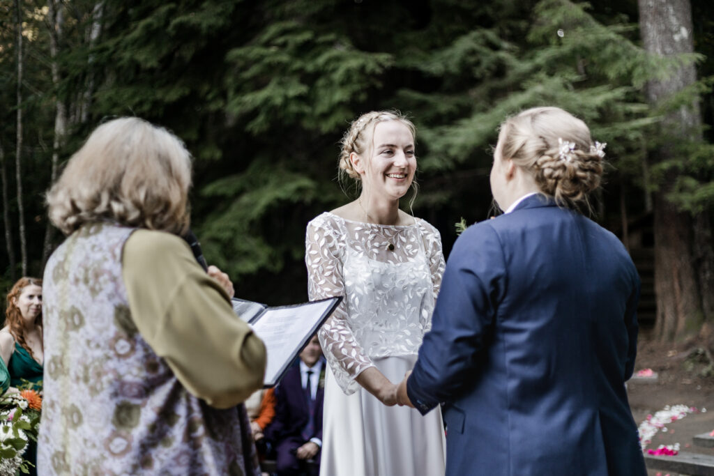 Morgan smiles at Kirsten as they hold hands at the altar at this Camp Elphinstone wedding.