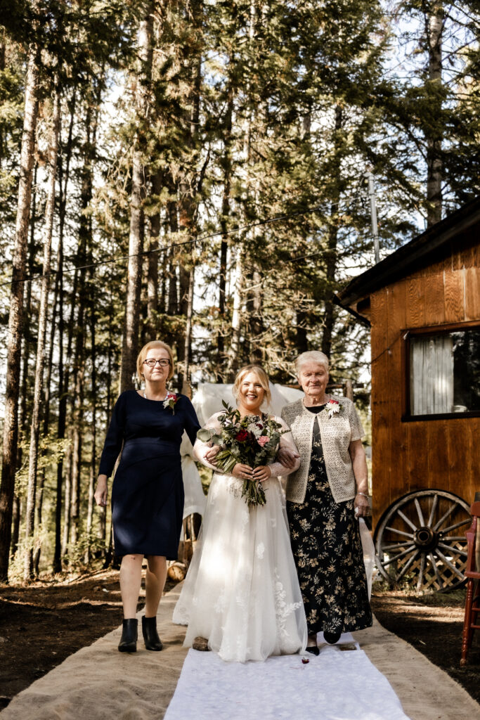 Bride walks down the aisle with her mom and grandma at this cabin elopement