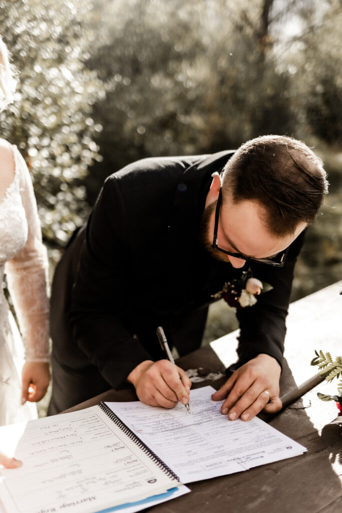 The groom signs the marriage papers at this cabin elopement