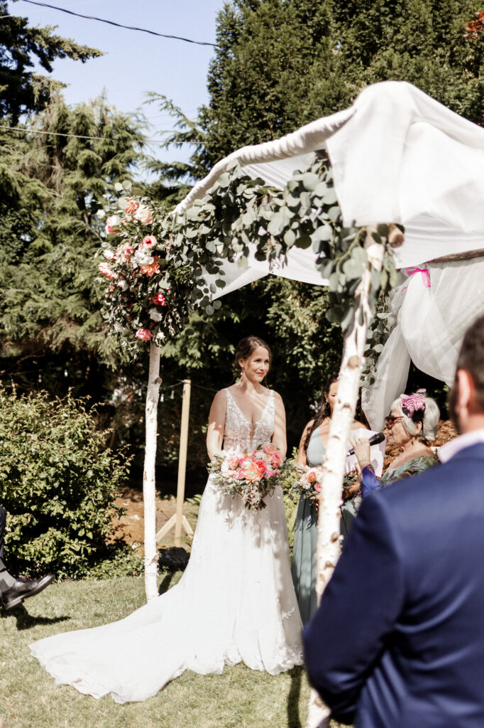 The bride gazes at her groom at the altar at their garden party wedding.