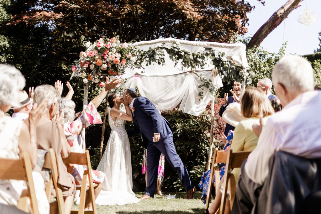 The bride and groom share a first kiss as a newly wed couple at their garden party wedding.