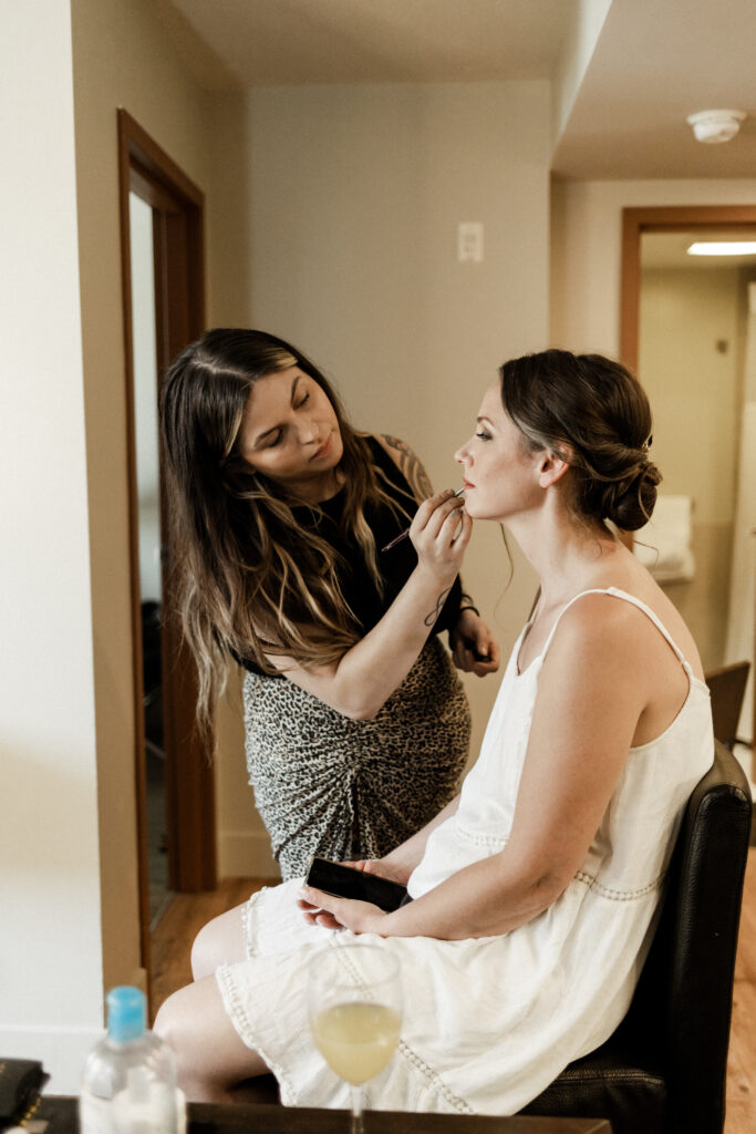 The bride gets her makeup done for her garden party wedding