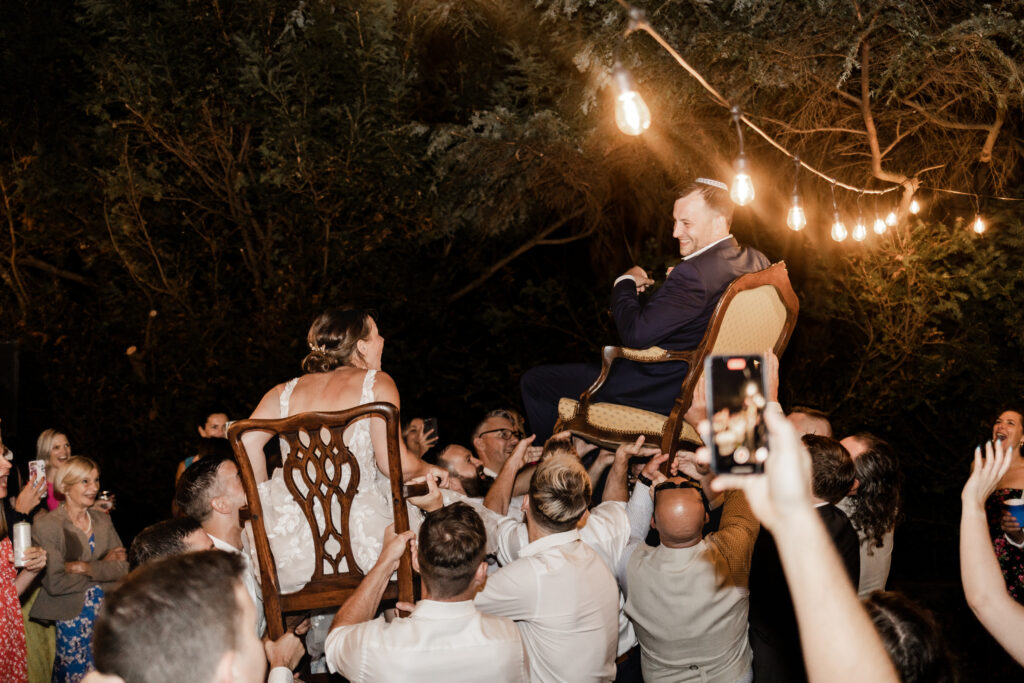 The newly wed couple are lifted up in chairs during the horah at their garden party wedding