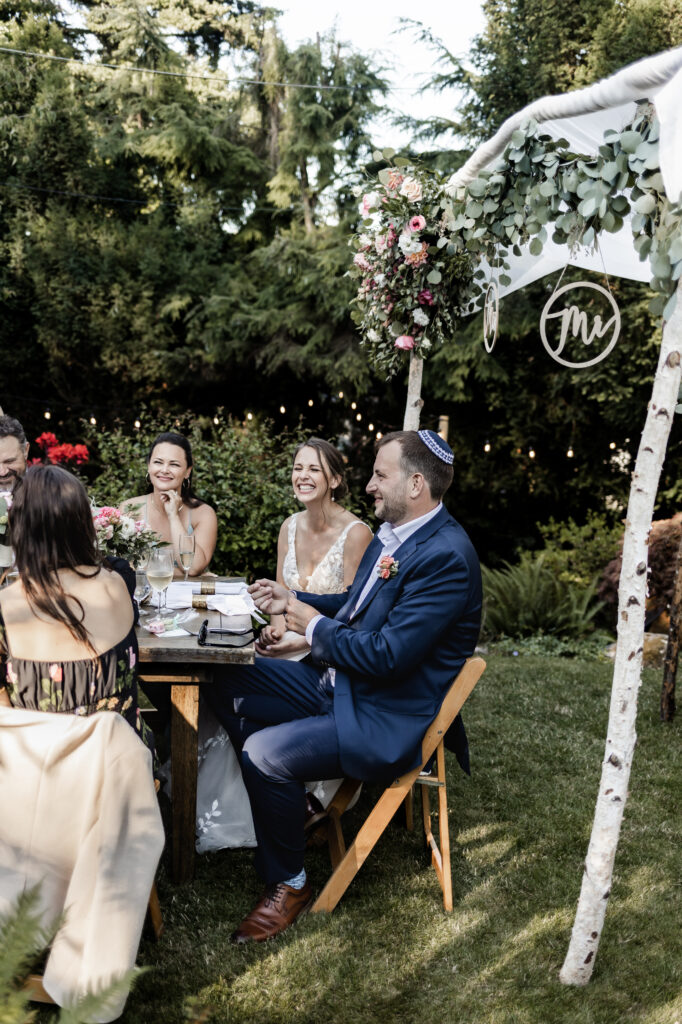 The newly weds laugh during their guests speeches at their garden party wedding