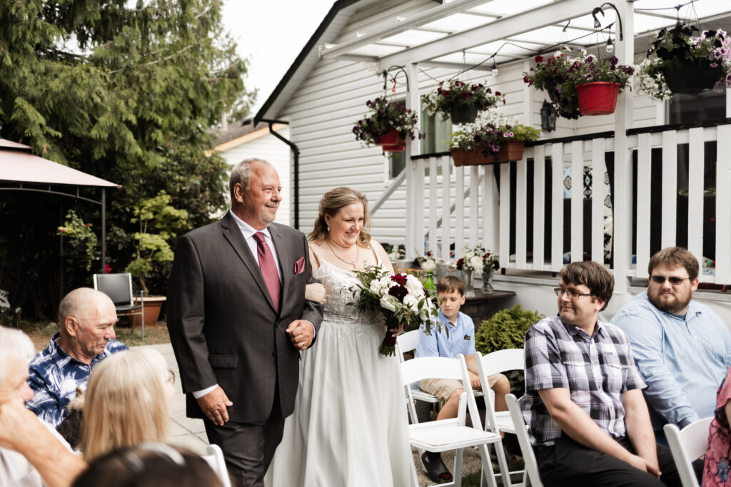 Bride walks down the aisle with her dad at her backyard wedding in Mission