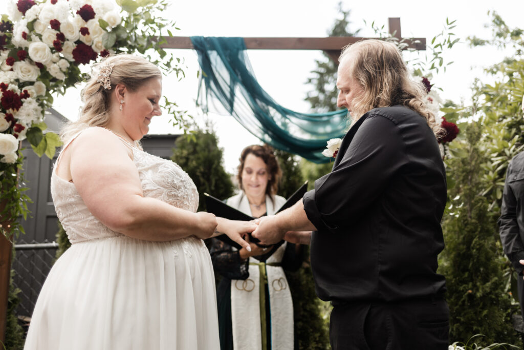 Bride and groom exchange rings at their backyard wedding in Mission