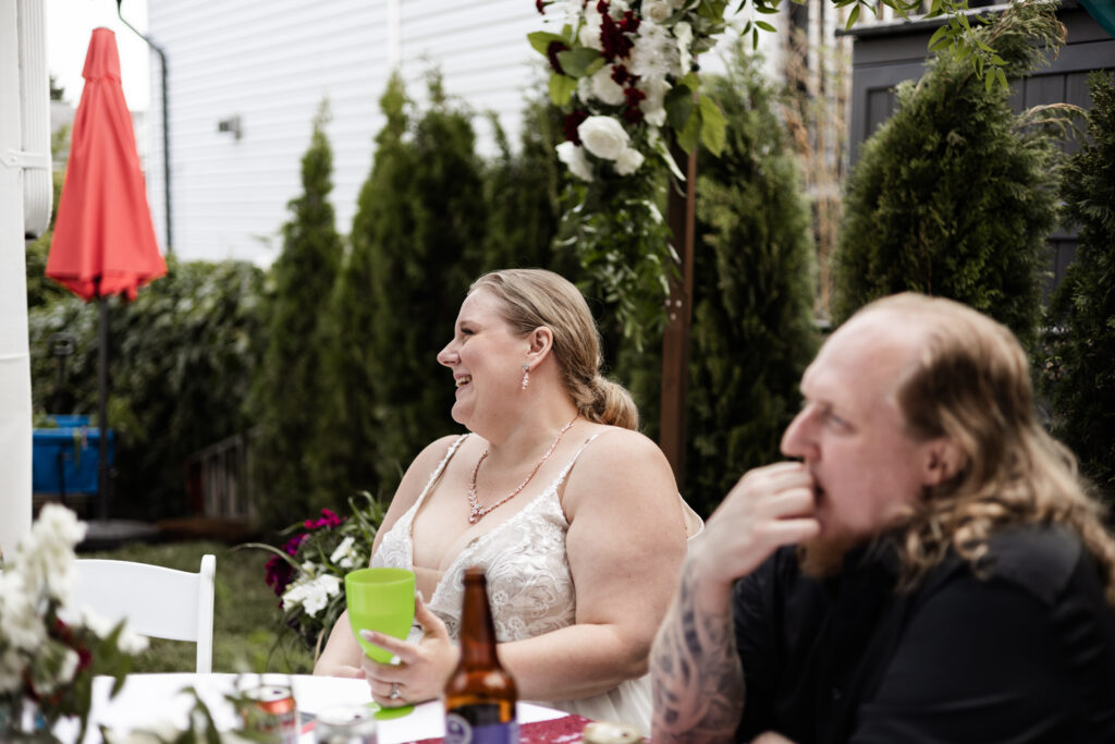 Bride and groom laugh during speeches at their backyard wedding in Mission