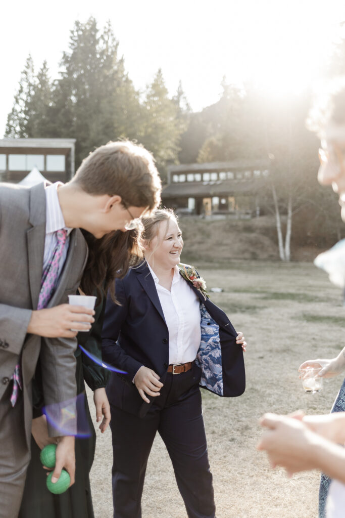 Kirsten shows off the pattern inside her suit jacket during cocktail hour at this Camp Elphinstone wedding.