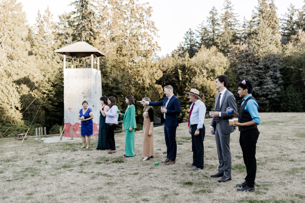 Guests line up to play bocce ball at this Camp Elphinstone wedding.