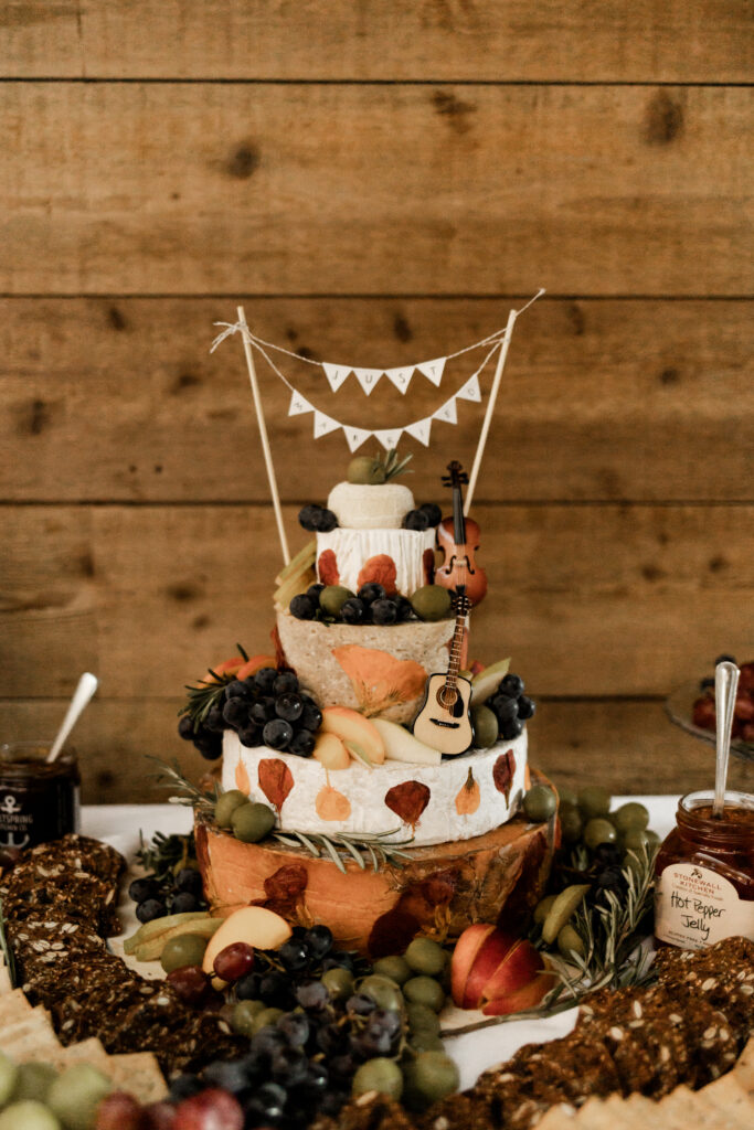 An upclose of the charcuterie cake topped with a "just married" banner at this Camp Elphinstone wedding.