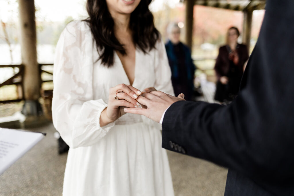 Bride and groom exchange rings at their Rocky point park wedding ceremony