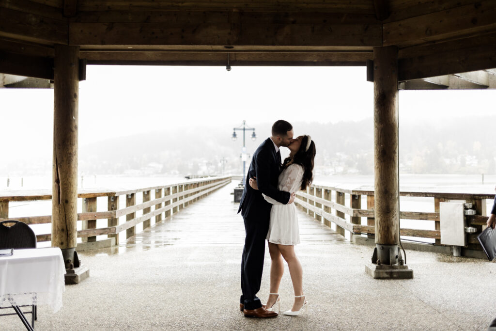 Bride and groom share a first kiss at their rocky point park wedding ceremony