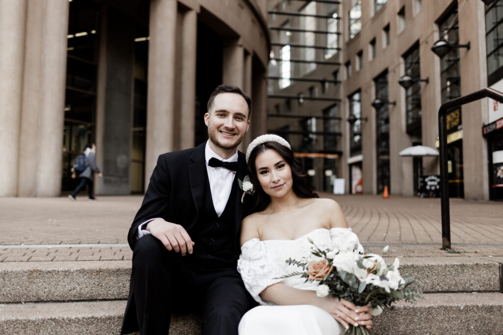 Bride and groom pose in front of the Vancouver public library at this downtown Vancouver wedding