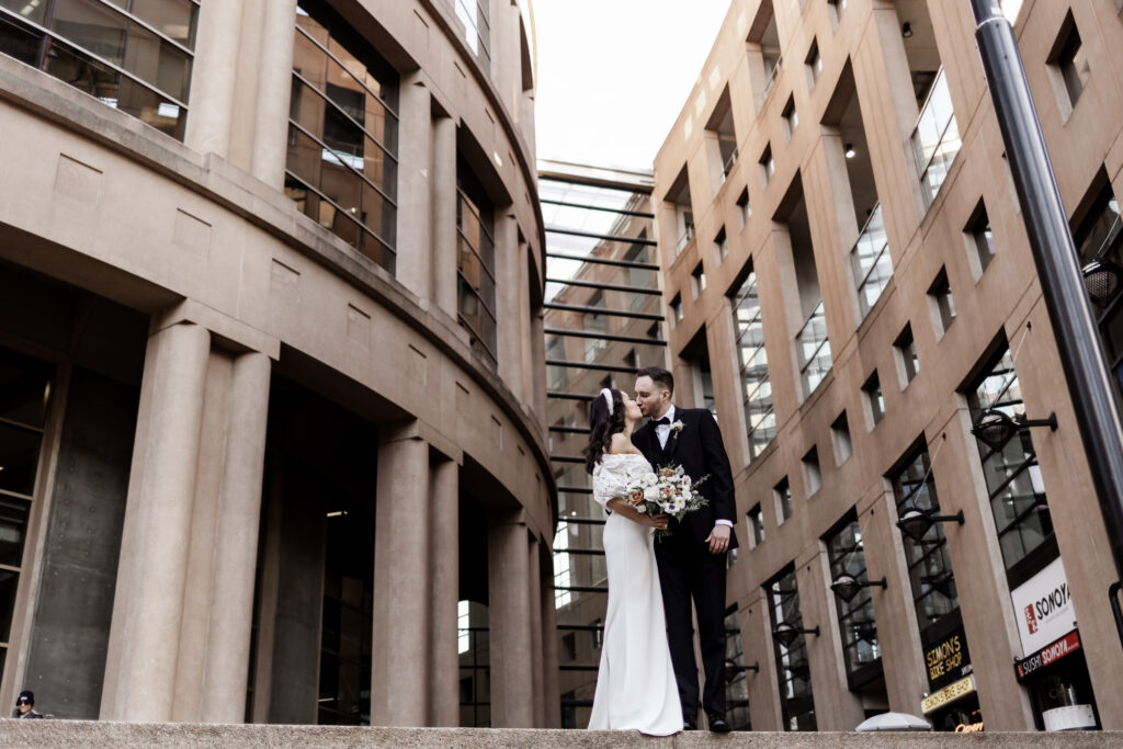 Bride and groom pose in front of the Vancouver public library at this downtown Vancouver wedding