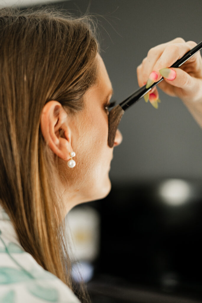 An up close of a makeup brush on the bride's face as she gets her makeup done for her Kildara Farms wedding