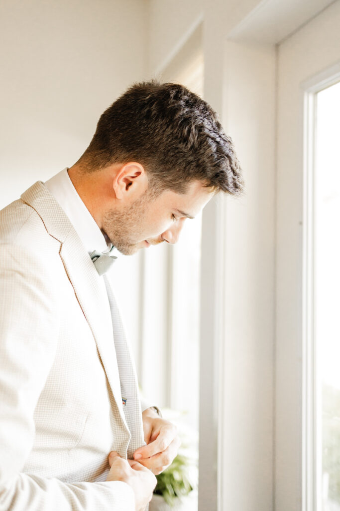 The groom does up the button of his suit jacket for his Kildara Farms Wedding