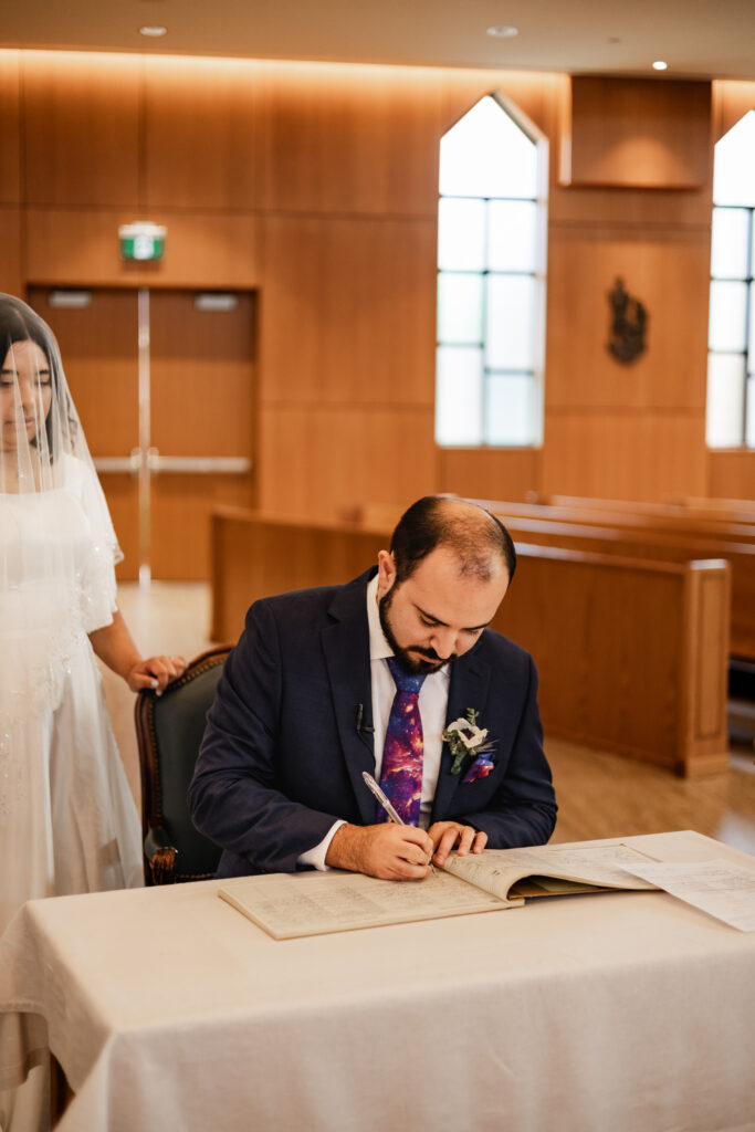 Groom signs wedding papers at his wedding at Seasons Restaurant