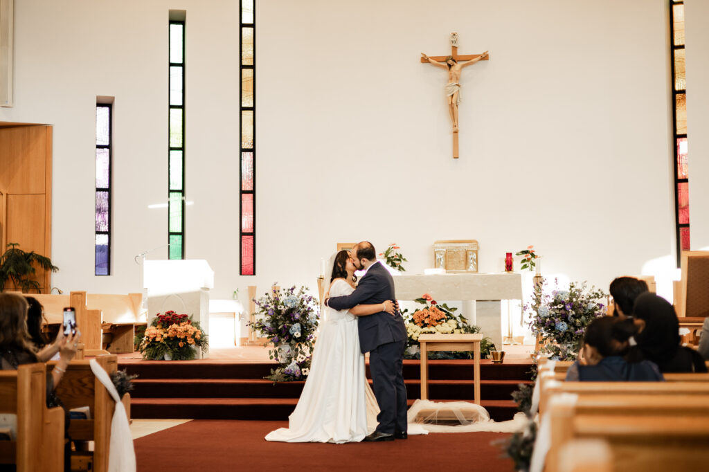 Bride and groom share a first kiss at St. Paul's Parish before their wedding at Seasons Restaurant