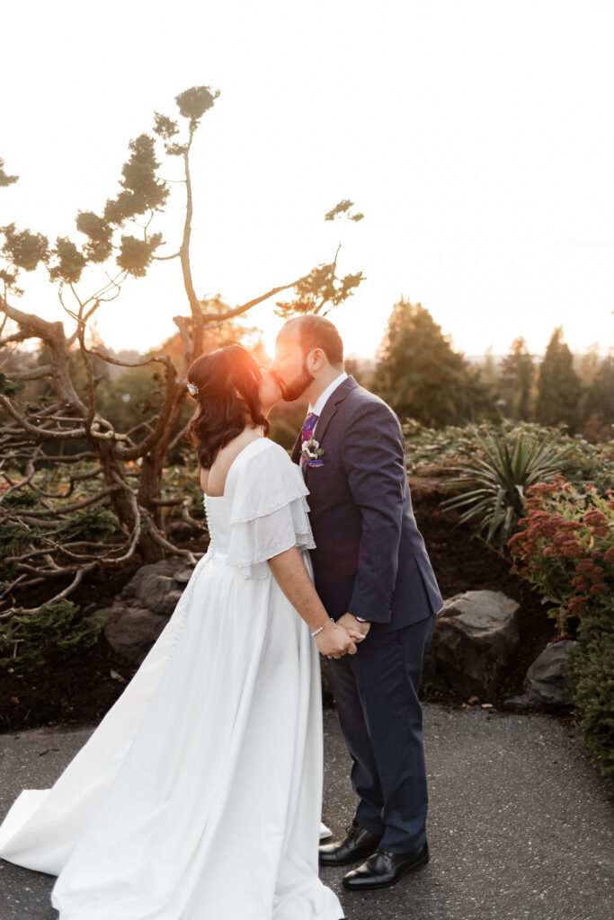 Bride and groom share a kiss as the golden suns shines in from behind at their wedding at Seasons Restaurant