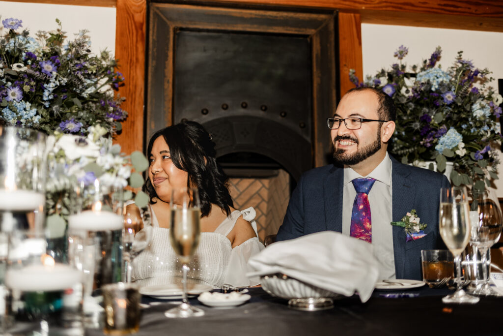 Bride and groom smile during speeches at this wedding at Seasons Restaurant