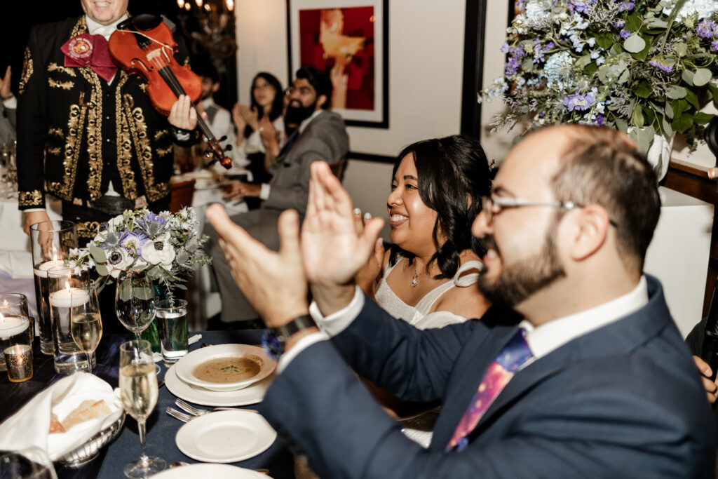 Bride and groom clap during mariachi band performance at this wedding at Seasons Restaurant