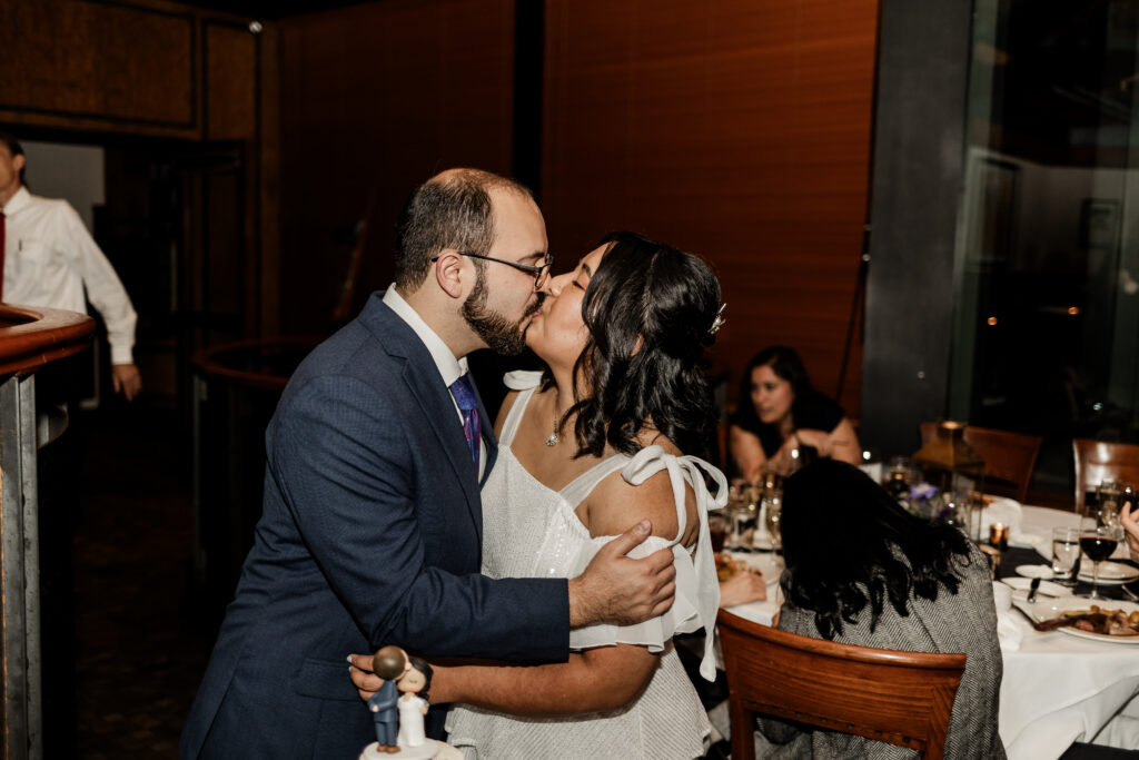 Bride and groom kiss after they cut their cake at their wedding at seasons restaurant