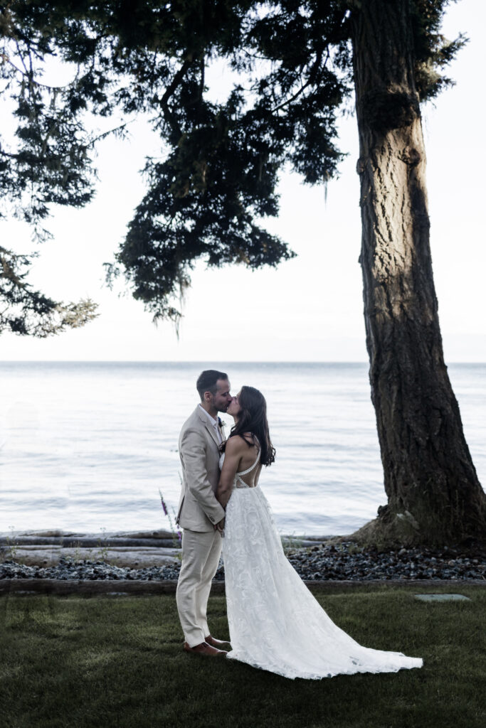 The couple share a first kiss in front of a goregous blue ocean backdrop at their east sooke elopement.