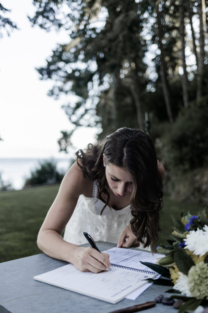 The bride signs the marriage papers at her east sooke elopement.