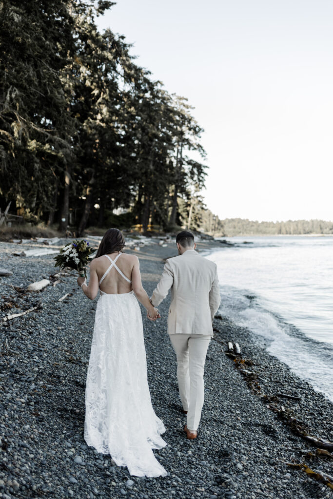 The bride and groom walk hand in hand down a rocky beach at their east sooke elopement.