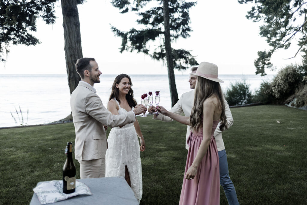 The newly married couple and their friends cheers their champagne glasses in celebration at their east sooke elopement.