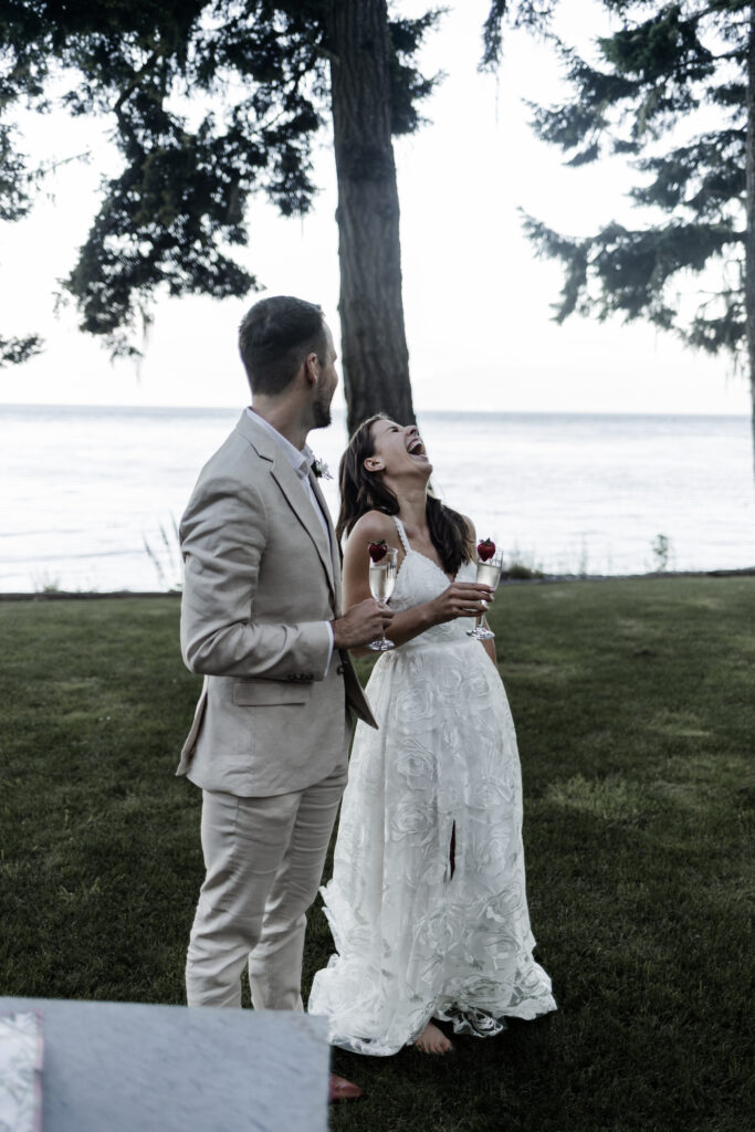 The bride leans back in laughter as their friends give a speech at their east sooke elopement.