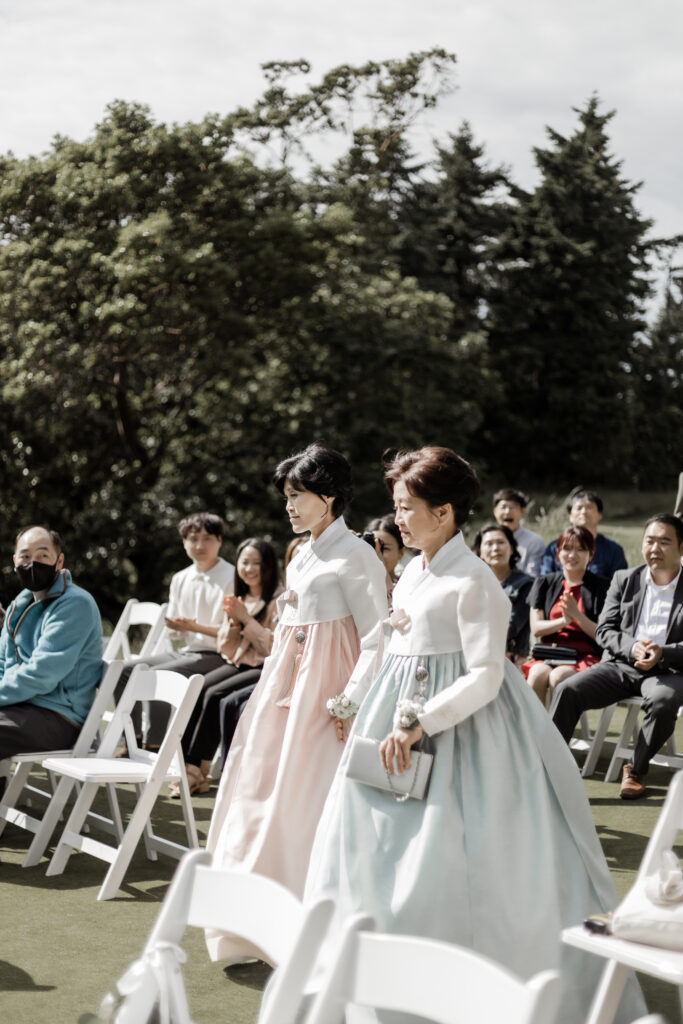 bride and grooms mothers walk down the aisle in matching dresses at this Olympic View Golf Club wedding