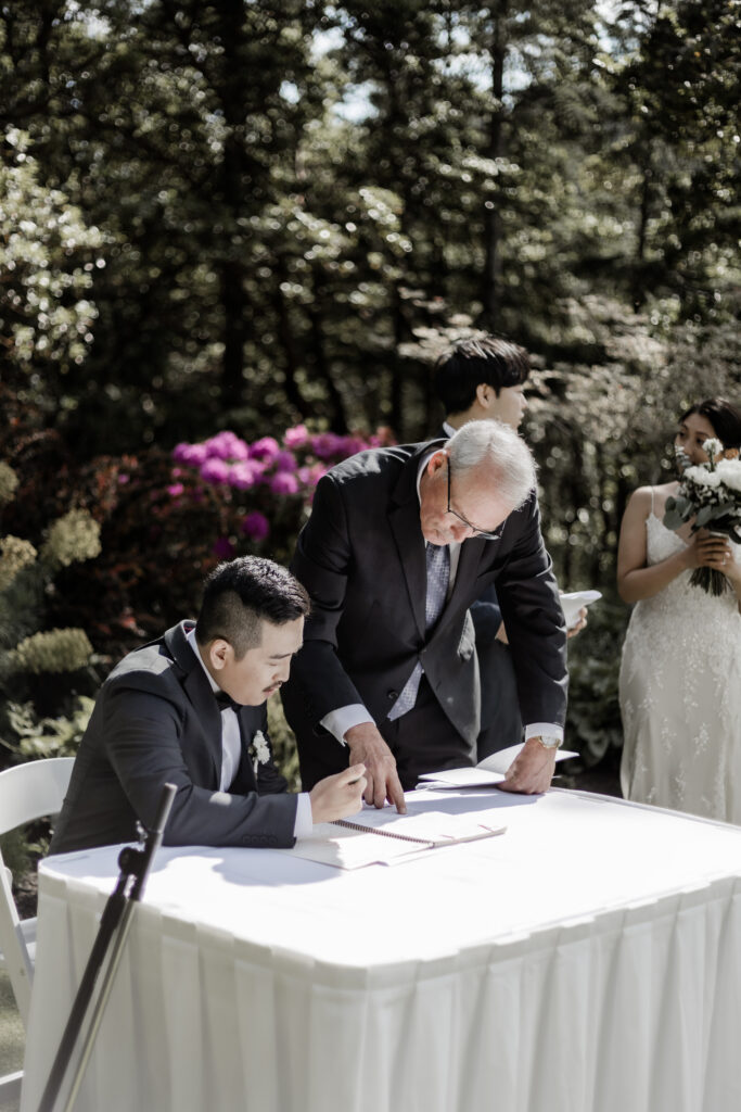 groom signs wedding papers at this Olympic View Golf Club wedding